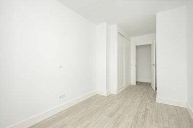 Empty white room with built-in wardrobes and wooden-like ceramic floors
