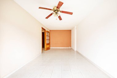 Room with two-tone paintings on the walls, fan lamp and dark mahogany wood doors