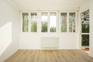 Living room with wall full of windows overlooking a patio with plants and trees