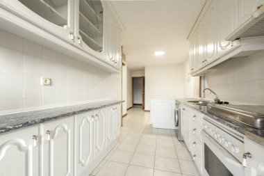 Elongated kitchen with white cabinets and gray countertops in a vacation rental apartment
