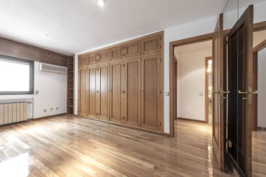 Room with large built-in oak wood wardrobe and oak parquet floors with air conditioning and heating