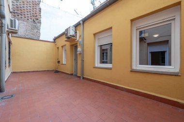 Ground floor house with several windows and patio with clay floors