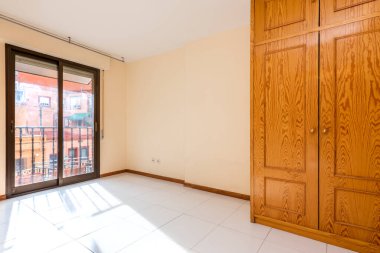 Penceresi ve çardağı olan boş bir oda ve çam ağacından yapılmış bir gardırop.