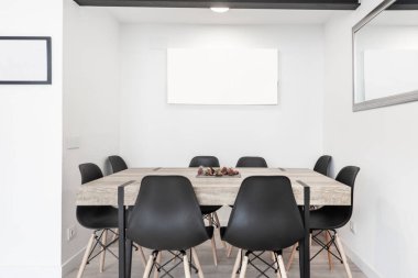 Gri bir odada yemek için sekiz sandalyeli modern estetik yemek masası.