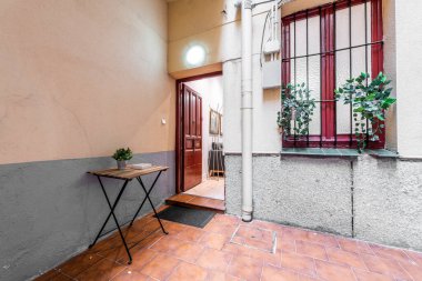 Terrazzo döşemeleri olan bir avlunun içindeki bir eve giriş.