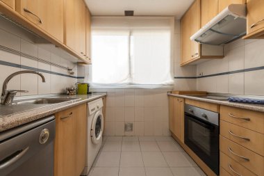 Kayın ağacı mobilyalı mutfak, pembe granit tezgah ve kiralık bir apartmanın penceresi.