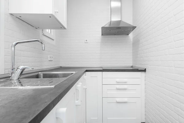 白いキャビネット 白いレンガの壁 灰色のカウンターとステンレス製のシンクと角の範囲フード付きのバケーションレンタルキッチン — ストック写真