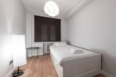 Gençlik odası beyaz kiremitli yatak, yerde ve tavanda kağıt lambalar ve koyu renk kör