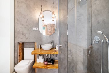 Verimli çam tezgahında sabunlu beyaz porselen lavabo ve gri Venedik sıva duvarları