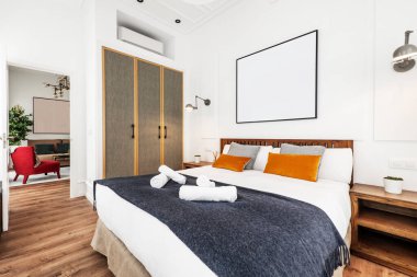 Mobilyalı, kısa süreli kiralık dairede, döşenmiş dolap kapıları ve dekoratif yastıkları olan büyük boy yatak.