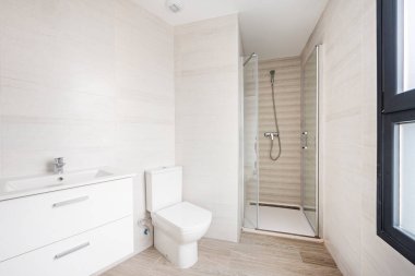 Banyo açık tonlu, beyaz asılmış dolaplı ve cam perdeli.