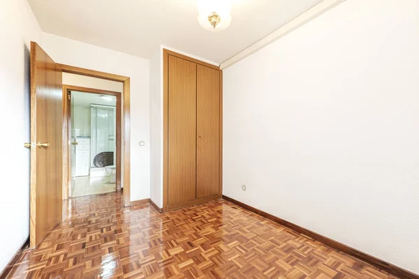赤いオーク材の床を持つ空の部屋 背景に2つの木製のドアとトイレ付きの組み込みのワードローブ — ストック写真