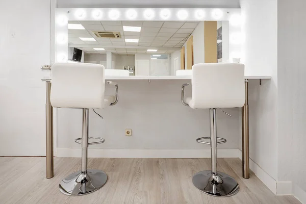 White chairs in front of a makeup mirror