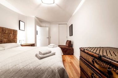 Büyük boy yataklı yatak odası, el yapımı hasır mobilyalar, kabartmalı yatak örtüsü, beyaz sürgülü kapılı gardırop.