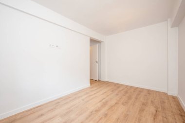 Yeni boyanmış beyaz duvarları ve meşe döşemeleri olan boş bir oturma odası.