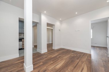 Boş bir oturma odası, bir köşede bir sütun ve duvarlarda bir kaç kirişli açıklık.