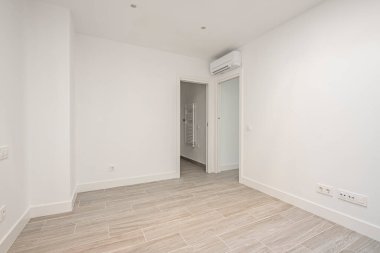 Porselen taş kaplamalı ve banyoya erişimi olan boş klimalı bir yatak odası.