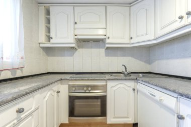 Dördüncü duvar dışında mobilya duvarları ve tezgahları olan mutfak odası.