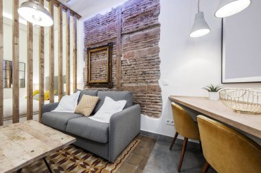 Çağdaş dekorasyonlu tuğla duvarlı apartman dairesi ahşap döşemeli ve kanepeli ayrılık.