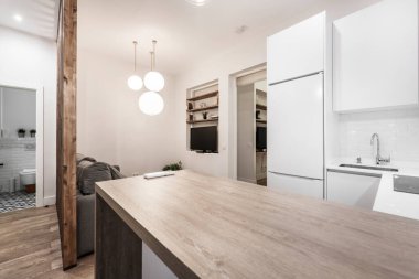 Kısa süreli kiralık bir dairede beyaz dolaplı mutfak masasının ahşap tezgahı.