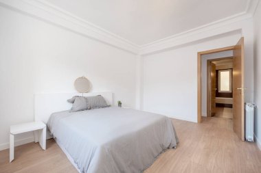 Gri yataklı yatak odası ve beyaz mobilyalı yatak örtüsü, alüminyum radyatör ve meşe marangoz.