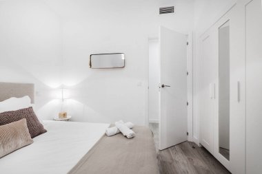 Gardıropla kaplı yatak odası, yastıklı ve havlulu kral yatağı.