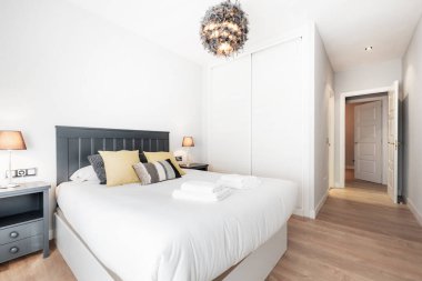 Yatak odası, büyük boy yatak odası, divanı, beyaz yorganı, sürgülü kapıları ve tuvaleti olan kiralık bir tatil dairesi.