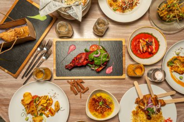 Ortasında tavuk tikka masala olan Hint yemekleri, doldurulmuş samosalar, kırmızı köri, korma, tarçın çubukları, pilav pilavı ve kavanozlarda daha fazla baharat.