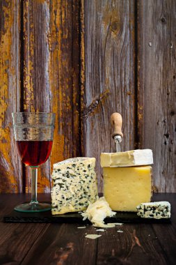 Lezzetli ve pis kokulu bir peynirli taco bir parça manchego peyniri ve peynir bıçağının yanında lezzetli bir peynir peyniri ve eski ahşap bir masada bir bardak İspanyol gülü şarabı.