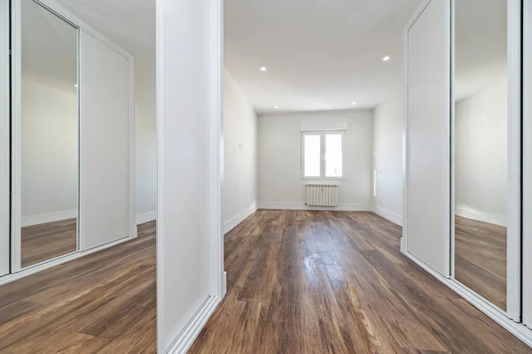木製のスライドドアと木製の床を持つ鏡付きの空のベッドルーム — ストック写真