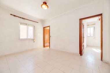 Alüminyum pencereli boş oturma odası ve beyaz taş kaplamalı diğer iki odaya giriş kapısı.