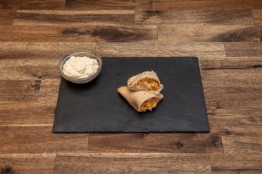 Hafif ahşap sehpası, gri kumaştan döşenmiş kanepesi, ahşap dolabı, ahşap zemini, kiralık bir dairede uyumlu mutfağı olan oturma odası.