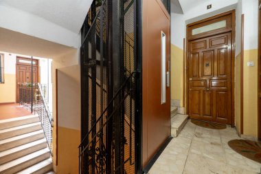 Kahverengi asansörlü ve ahşap kapılı bir apartmanın ortak alanları.