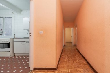 Meşe parke zemini ve kil terrazzo zeminli mutfağa erişimi olan bir apartman dairesinin koridoru.