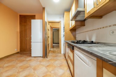 Geleneksel ahşap süslemeli mutfak ve gri tezgahlı, beyaz aletli ve ahşap mobilyalı taştan yapılmış döşemeler.