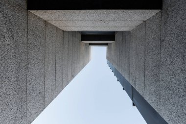 Çelik ve granitten yapılmış bir ofis binasının ön cephesinin düşük açılı çekimi.