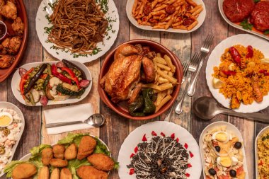 Çeşitli İspanyol yemekleri ve kızarmış tavuk ile ev yapımı patates kızartması ve kızarmış yeşil biber. Paella tabağı, deniz ürünleri, sucuklu makarna makarna, makarna salatası ve çatal bıçak takımı.