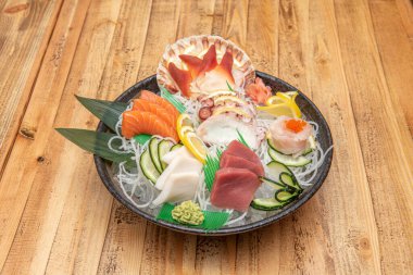 Yuvarlak suşi tepsisi, ahtapot sashimi, kelebek balığı, mavi yüzgeçli ton balığı, Norveç somonu ve wasabi ve zencefilli istiridye.