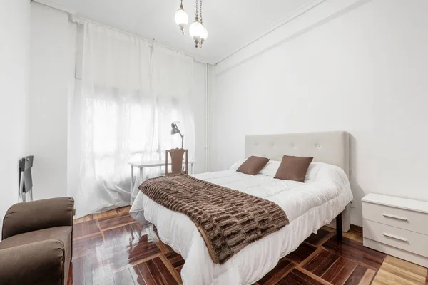ベッドルームには 白い羽毛布団付きのベッド 一致するクッション付きの茶色の毛布 白い研究テーブルとオークの寄木細工 — ストック写真