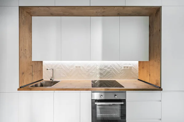 スチールシンクとオーブンとカウンタートップによって白いキャビネットや木枠付きのキッチン — ストック写真
