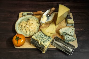 Peynir çeşitleri bıçaklı, domatesli, mavi peynirli, parmesanlı peynirli ve ahşap kazıyıcılı.