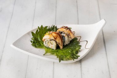 Yılan balığı sarılı uramaki dürümü, krem peynirle ve Shiso yaprağı üzerine özel sosla tamamlanmış.