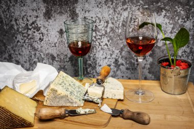 İspanyol şarabı, Manchego peyniri, Fransız küflü peyniri ve dekoratif spatifillo soslu Brie peyniri ile dolu bir masada.