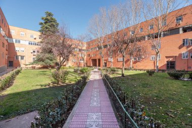 Bahçelerle ve kırmızı kiremitlerle dolu ağaçlarla dolu ortak alanları olan konut binalarının ön cepheleri.