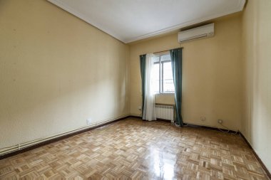 Alüminyum pencereli, yeşil perdeli, beyaz perdeli, meşe parke zeminli boş bir oda.