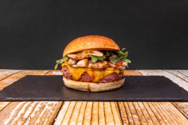 Duble çedar peynirli lezzetli sığır burger, haşlanmış mantar, roka ve barbekü sosu.