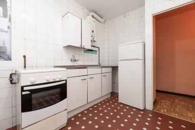 Mobilyalı mutfak ve beyaz tonda buzdolabı. Detaylar ve kenarları siyah. Metal bir mutfak ve beyaz dokunuşlu kil terrazzo zeminli beyaz kare fayanslar.