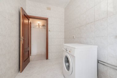 Taş kaplamalı, duvarları uyumlu ve koyu ahşap kapılı çamaşır makinesi olan bir oda.