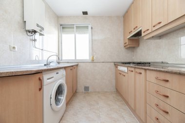 Hafif ahşap mobilyalı mutfak, pembe granit tezgah, taş kaplamalı beyaz eşyalar.