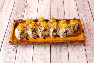 Soya soslu Uramaki ejderi suşi, avokado, nori yosunu, kırmızı ton balığı, ahşap tabakta soğan, krem peyniri ve beyaz masa.